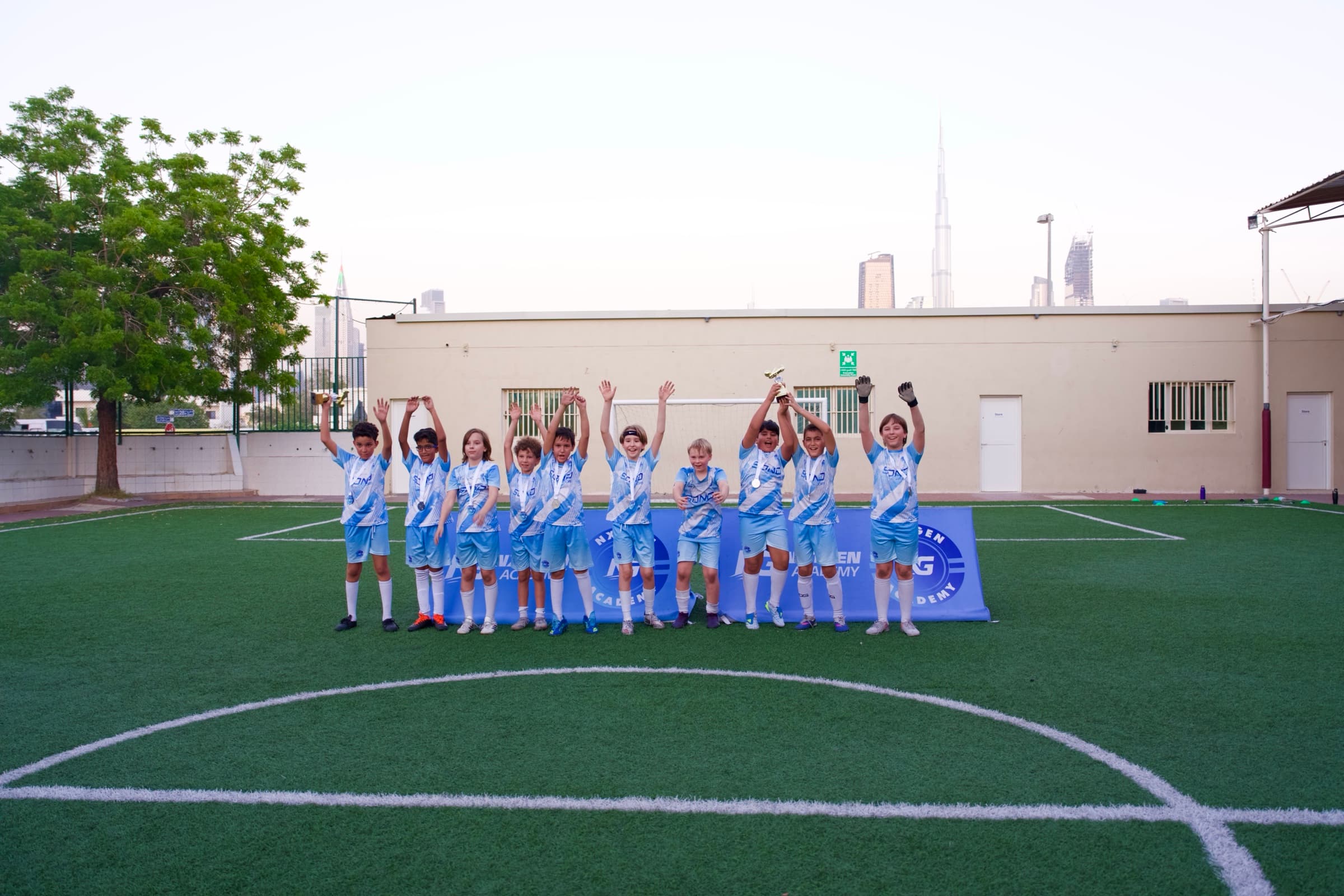 NXTGEN Holiday Camps players celebrate together with their medals and trophy.
