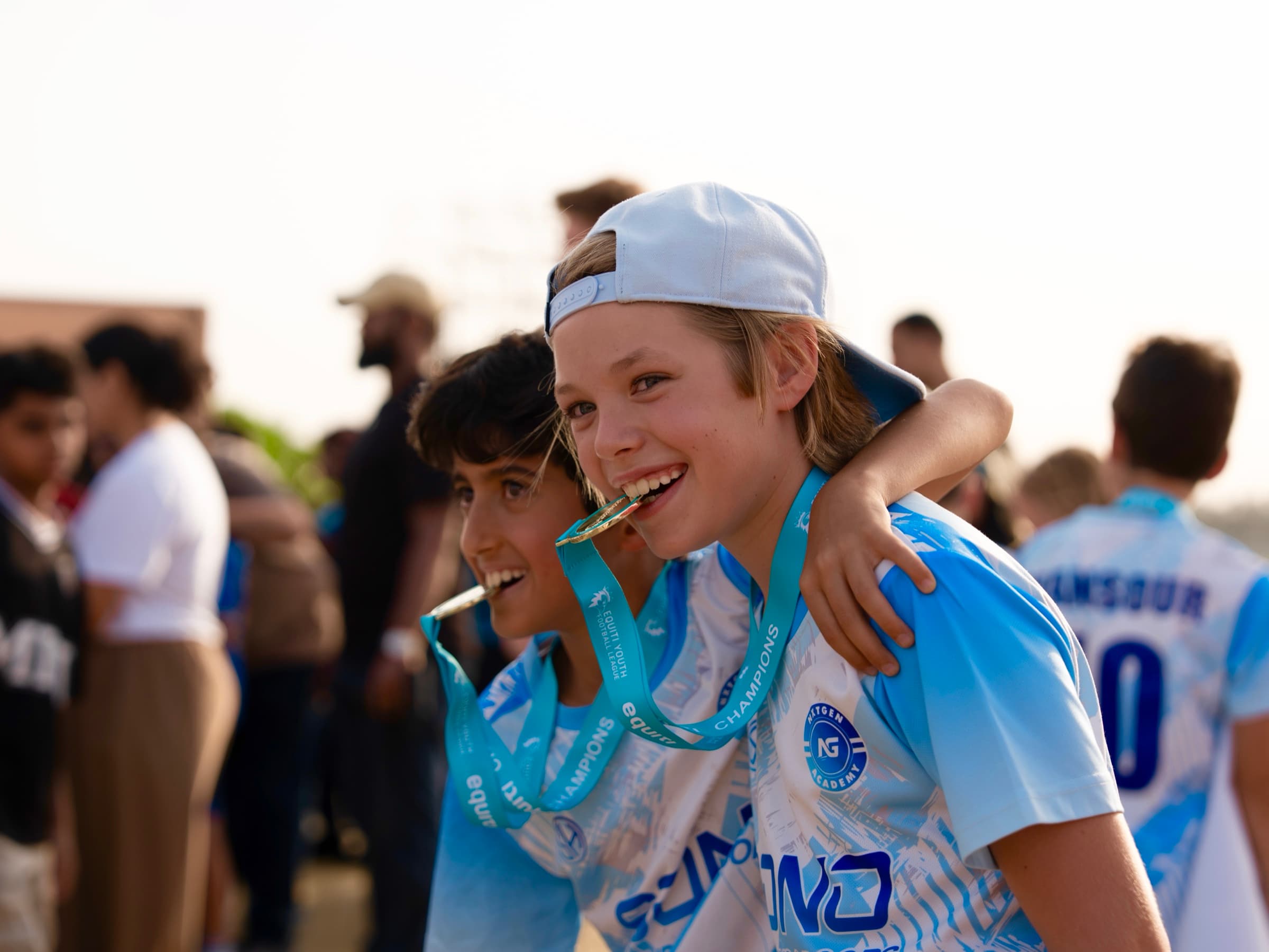 Two smiling NXTGEN Squad players celebrate together with their medals.