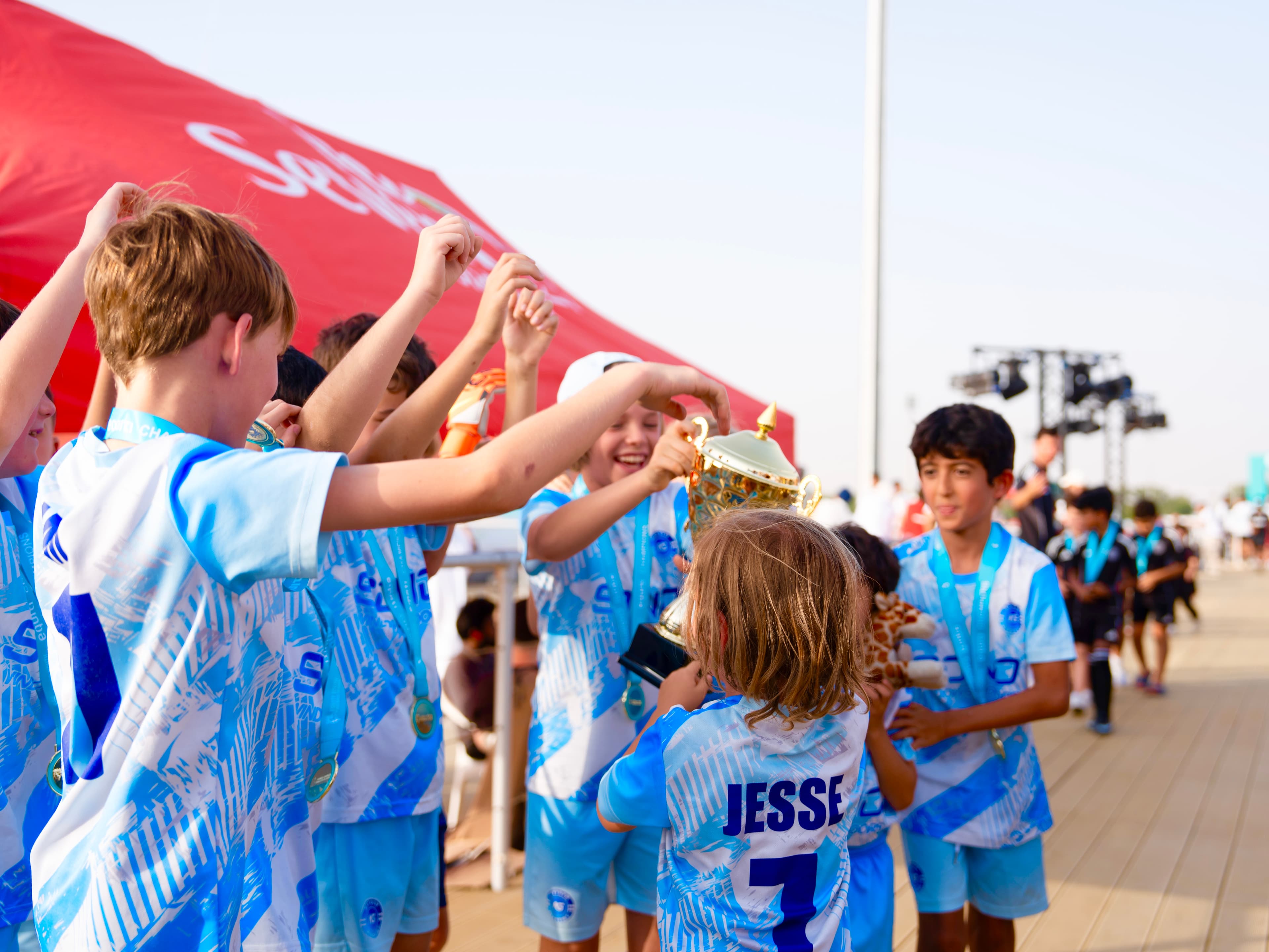 NXTGEN players celebrate together around their trophy after a tournament.